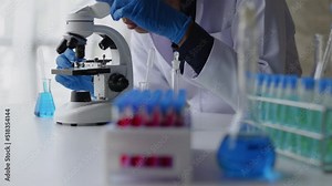 Male scientist using microscope for observation on simple test in laboratory table that full of test tubes and beakers. Stock Video