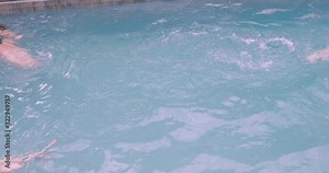 Four young friends give an exploding fist bump in a pool and swim away in synch