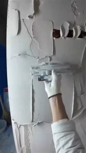 Skill profesional smoothing thick white plaster layer on a curved column with wide trowel