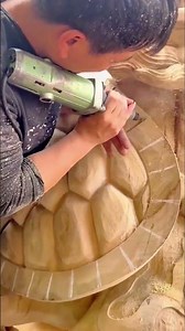 carving a large wooden turtle shell using a power tool with precision