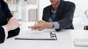 Financial advisor pointing at contract for client to sign during meeting.