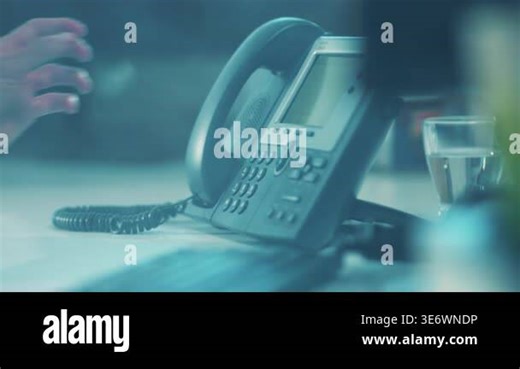 desk phone on dim table, abandoned reception scene with offhook handset, coiled cord resting, blurred glass cup Stock Video Footage - Alamy