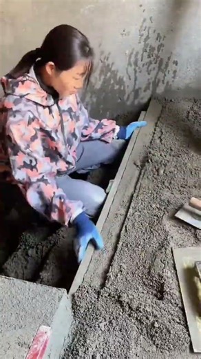 Female Construction Worker Leveling Wet Concrete Floor Surface Using Metal Tool