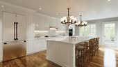 Traditional white kitchen with long island and wooden chairs with...