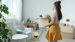 Slow motion of new house owner carrying carton box indoors in light studio relocating moving belongings. Lifestyle and accommodation concept.
