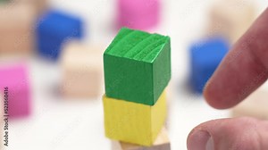 Assembling a toy colored wooden block tower with multicolored cubes. Hand sets the green top of the wood structure close-up. Development, environment and creativity concept. Conceptual view Stock Video
