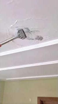 Removing damaged ceiling plaster using scraper for smooth repair