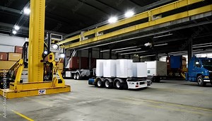 An automated robotic system efficiently loading and unloading trucks at an industrial loading dock, with no human workers present.