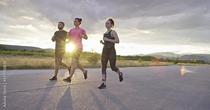 Multiethnic group of athletes running together on a panoramic countryside road. Diverse Team of joggers on morning training.