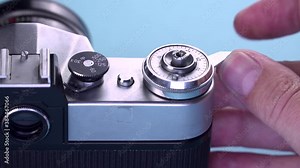 The photographer prepares the hand shutter for shooting and press the button Shutter release it on a vintage 35mm film analog camera. Close-up