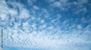 Seamless time lapse of white cirrocumulus clouds that flow continuously in loop from right to left in the blue sky
