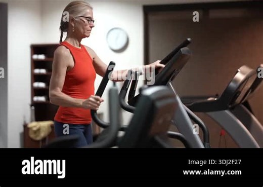 Mature woman engages in regular exercise on an elliptical trainer at the gym to improve fitness and build strength Stock Video Footage - Alamy