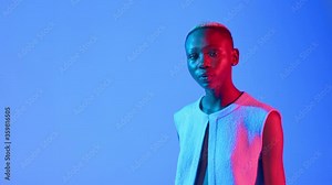 Fashion and beauty concept as a Black female model walks towards camera and poses on a blue background with copy space.