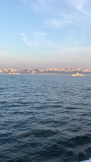 Serene Ocean View with Cityscape and Sailing Boat