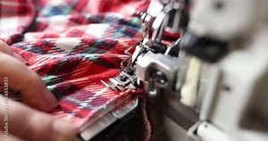 Seamstress sews checkered clothes in a studio on a sewing machine