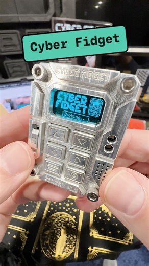 The Cyber Fidget is a digital option for restless hands. It’s a programmable pocket-sized metal gadget designed with buttons, a slider, and an OLED screen. Priced at $179, this is an expensive fidget toy. But there is a 3D-printed shell version and even just the board for less money. #ces2026 #fidgettoys #3dprints | The Verge