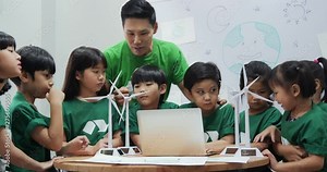 Teacher explaining to student in classroom about ecology project. Technology and Education concept.