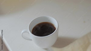 woman raises a filter with coffee over a cup, drops of coffee dripping into a cup. pouring homemade filter coffee. closeup white cup with paper filter with coffeeground. brewing filter coffee at home