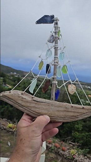 Handmade sailboat using driftwood and nylon cord with sea glass, sea tiles, and seashells.