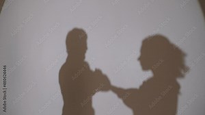 Dancing shadows on the wall guy and girl. Two silhouettes of young people. Reflection of a dancing pair of shadows on the wall.