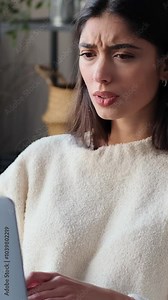 Unhappy young adult Caucasian woman working with laptop and upset by bad news at home. Concept of a failure or problem. Vertical video.