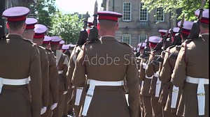 Army Soldiers stood during ceremony. They are stood in formation in uniform with rifles. Their backs are to the camera