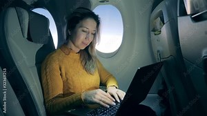 Aircraft cabin with a lady working on a laptop during her flight