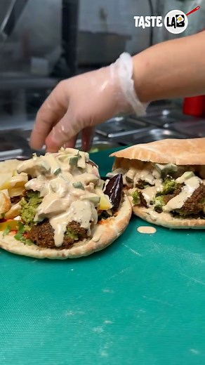 Soft round pita, loaded with fresh tomatoes, crunchy pickles, grilled veggies and extra crispy falafel balls… all drenched in a creamy, tangy sauce. It’s a full-on flavor explosion.🔥 📹: kees_falafel / IG | Taste Lab