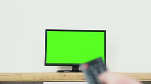 Watching chroma key TV and changing channel by remote control. Channel surfing internet TV green screen
