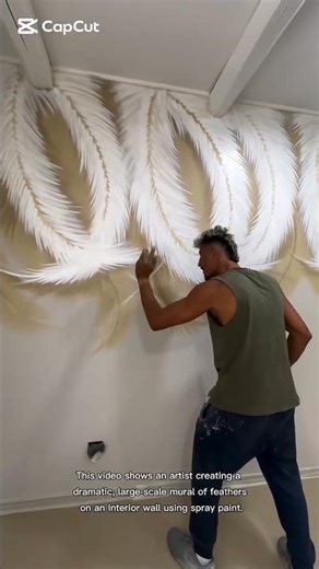 artist creating a dramatic, large-scale mural of feathers