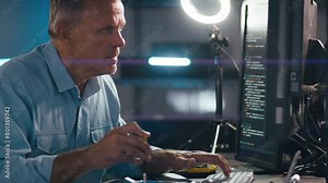 Close up of male electronics engineer using screwdriver and diagnostic software to repair laptop with low key lighting - shot in slow motion