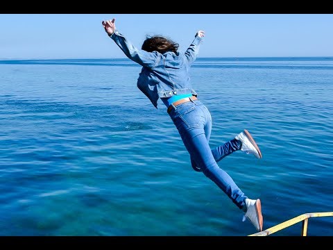 cheerful girl in wet denim jacket and wet jeans tenderly poses on the sea for wetlook video