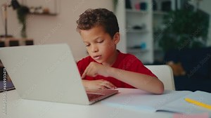 Little boy working on laptop pressing computer buttons, learning to use software