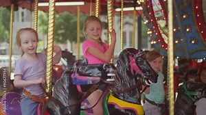 Three girls sitting on a carousel and waving