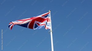 Flag of the United Kingdom or Union Jack waving in wind against clear blue sky
