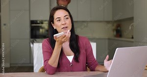 Positive Hispanic woman holding cellphone, lead business talk on speakerphone, explain contract details to colleague, working remotely from home office using easy and comfortable communication method