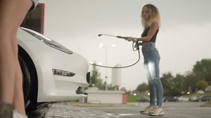 Beautiful girls washing car with high pressure water jet at car wash.