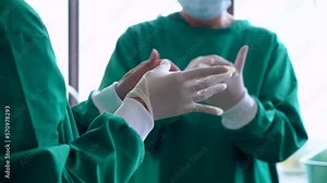 4K, Close-up of doctor and nurse assistant, who is wearing rubber gloves, for performing surgery in operating room, clean prepare for surgery, everyone was wearing green clothes for surgery as well.