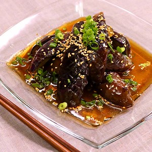 『さっぱりジューシー！ピリ辛ナスの中華風おひたし』 暑い日にはピリ辛さっぱり！ 【材料】 2人前 ナス 3本 ごま油 大さじ2 ①酒 大さじ1 ①砂糖 大さじ1 ①酢 大さじ1 ①しょうゆ 大さじ1 ①鶏ガラスープの素 小さじ2 ①水 大さじ1 ①ラー油 小さじ1 ----- トッピング ----- 万能ねぎ（小口切り） 適量 白いりごま 適量 【手順】 ナスはヘタを切り落とします。 1. ナスは縦半分に切り、皮目に格子状に切り目を入れ、さらに縦半分に切ります。 2. ①を全て合わせ、ラップをし、600Wのレンジで1分加熱します。 3. フライパンでごま油を中火で熱し、1を炒めます。 4. 3が全体的にしんなりしてきたら、熱い内に2に入れて全体を馴染ませ、粗熱を取ってから冷蔵庫で30分程冷やします。 5. 4を皿に盛りつけ、トッピングをして出来上がりです。 【コツ・ポイント】 ナスの皮目に格子状に切り目を入れることで、味の馴染みが良くなります。 ナスはすぐに調理する場合はアク抜きは不要ですが、色の変色や気になる方は水にさらしてください。 ラー油の量はお好みで調節してください。 ————