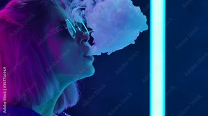 Portrait of a young stylish woman in sunglasses smoking a hookah and blowing out puffs of smoke. Close up. Slow motion.
