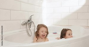 Fun games in the bathroom of the twins in quarantine. Happy kids as they bathe in the bathroom with foam. Horizontal video