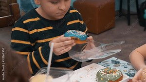 Cute little boy putting doughnut to plastic box. Adorable preteen boy putting donut to take away container after culinary master class
