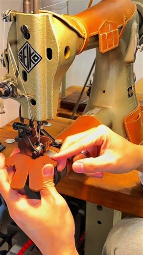 Stitching thick brown leather with heavy-duty SEIKO industrial sewing machine guided by careful hand