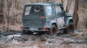 SUV drives forward on off road, splashing mud to sides. Car participating in off-road racing drivings dirty road and goes forward. High quality 4k footage