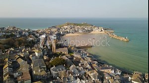 Cinematic drone and aerial footage over St. Ives. Beach in North Cornwall. Green seas and blue skies and surfers enjoying the waves