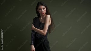 A young beautiful sensual female model poses on a dark green background. Fashion shooting in the studio.