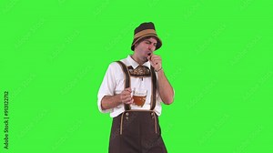 young bavarian man pretending to sing with microphone while having fun at oktoberfest chroma key