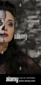 A mesmerizing woman with half her face adorned in intricate skeleton makeup makes a haunting shh gesture against a dramatic black brick wall. This Halloween-inspired portrait radiates an eerie allure, blending gothic beauty with a chilling atmosphere