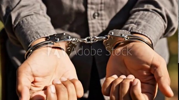 Person in handcuffs with hands bound at the front outdoors in a closeup scene highlighting restraint and tension