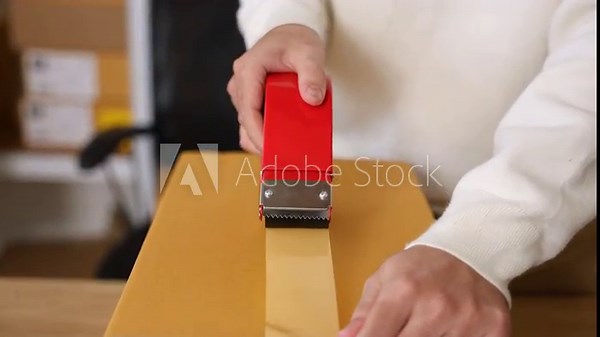 Warehouse shipping workflow showing young worker attaching label to parcel, preparing delivery orders, managing ecommerce packing process, supporting logistics operation in small business storehouse